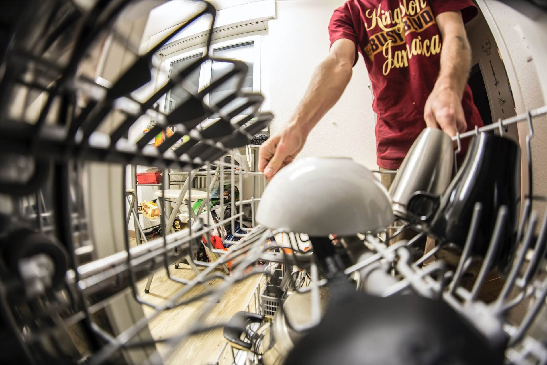 A point of view of a person loading the top shelf of a dishwasher