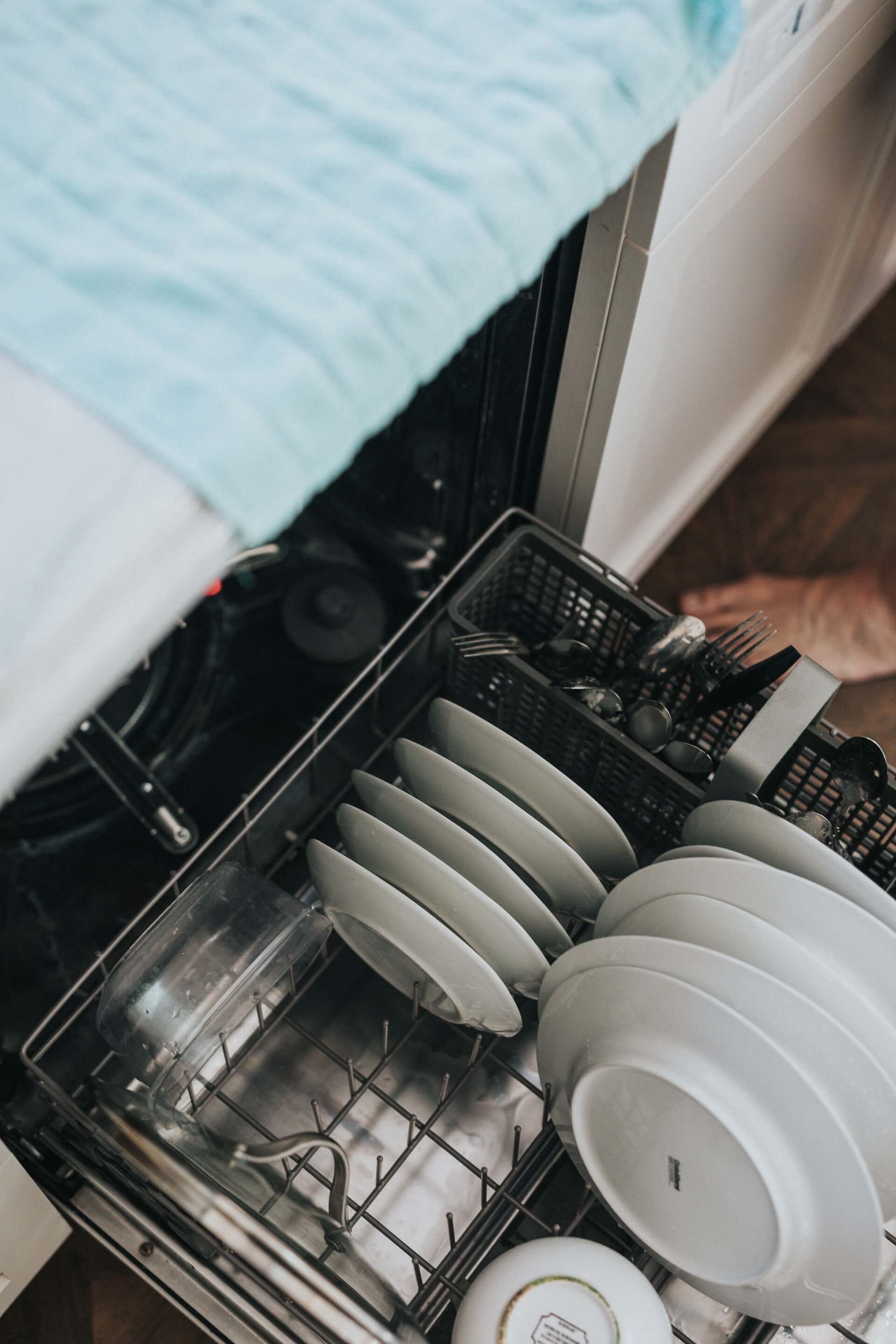 A top view of the dishes and cutlery placed in the bottom shelf of a dishwasher