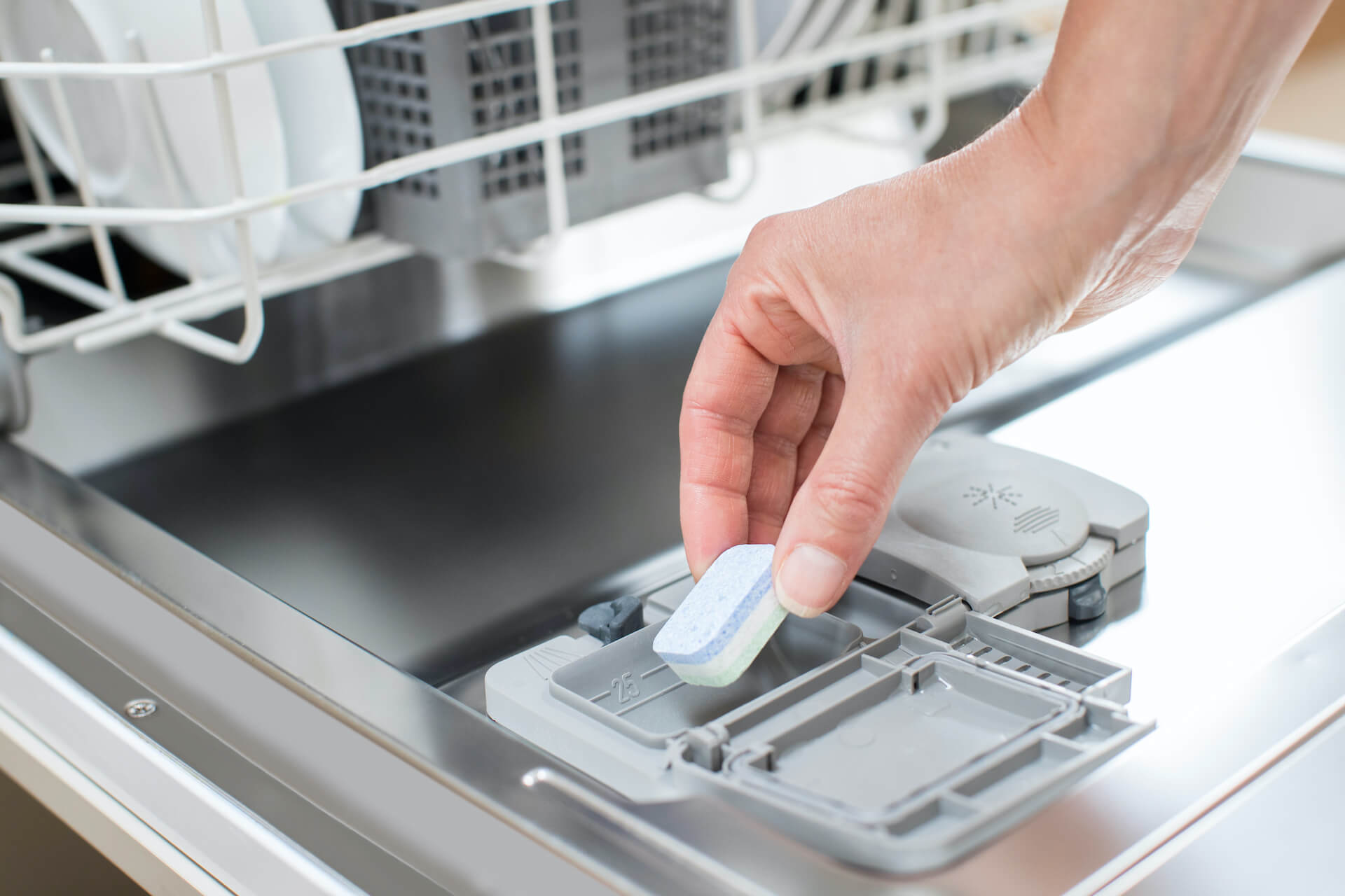 A person placing a dishwashing tablet in the dishwashing tablet dispenser